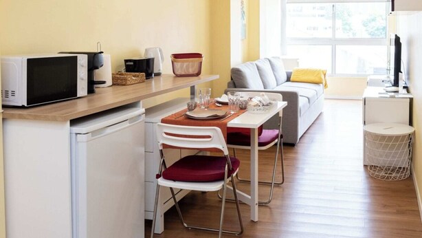 Um espaço compacto com cozinha compacta, área de refeições e espaço para sentar.