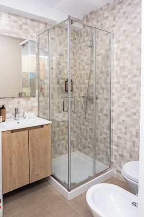 Ein modernes Badezimmer mit einer in Glas eingefassten Dusche, einem hölzernen Waschtisch und einem weißen Waschbecken.