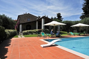 A swimming pool with lounge chairs and umbrellas, a stone building with a tiled roof, and a well-maintained garden. - Luna - Villa Cenami - big POOL with view (Massarosa)