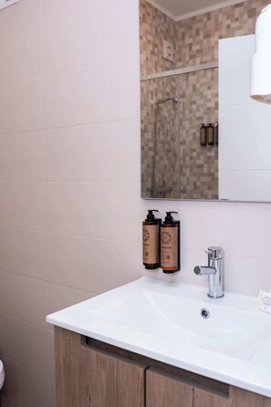Ein Badezimmer mit einem weißen Waschbecken, einem Spiegel und zwei Seifenspender.