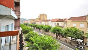 Una calle bordeada de árboles y edificios, cielo despejado y un edificio a lo lejos.
