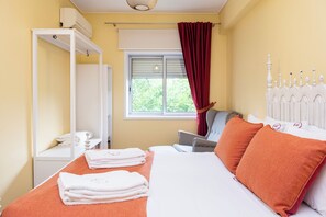 Ein Hotelzimmer mit einem Bett, einem Vorhangfenster, einem weißen Heizkörper und einer weißen Kopfteil.