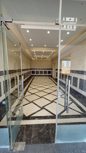 A hotel lobby with a check-in desk, a glass partition, and a patterned floor. - 2-bedroom apartment with AC in Down Town New Alamein (New Alamein)