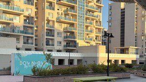 Un edificio residenziale a più piani con balconi, un cartello con la scritta 'Downtown By Cityscape' e aree salotto all'aperto.