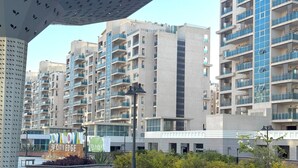 Un moderno palazzo residenziale con numerosi balconi, una zona esterna coperta con panchine e un cartello che indica 'Downtown by CityEdge'.