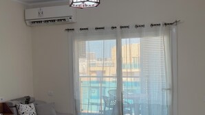 Una camera da letto con un letto, un comodino, una finestra con tende leggere e un condizionatore d'aria.