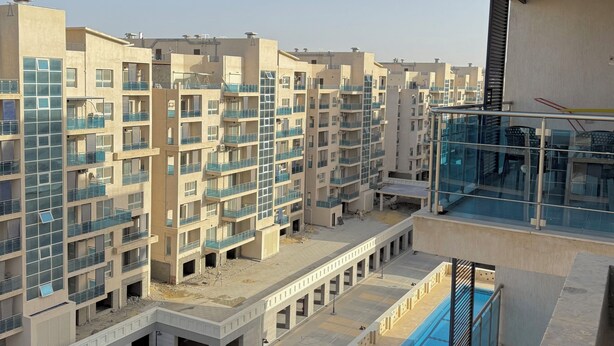 Un edificio residenziale a più piani con balconi, una piscina e un'area esterna coperta.