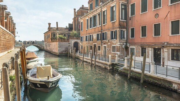 Un canale a Venezia con barche, edifici storici e un ponte.
