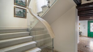 Una scala a chiocciola con ringhiera in vetro, una porta verde e due quadri appesi al muro.