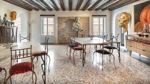 Una stanza con un tavolo lungo, sedie, un pavimento a mosaico e un muro in mattoni.