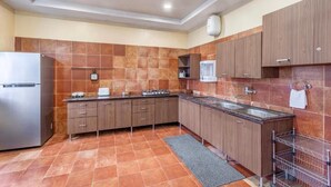 A modern kitchen with a stainless steel refrigerator, wooden cabinets, a gas stove, and a sink. - ELIVAAS Lakeview Manor 3-BHK Luxurious (Bhimtal)