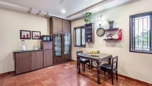 A kitchen with a dining table, cabinets, and a ceiling fan. - ELIVAAS Lakeview Manor 3-BHK Luxurious (Bhimtal)