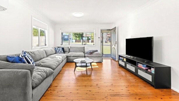 A modern living room with a grey sectional sofa, a coffee table, a flat-screen TV, and a wooden floor. - Poppi's Paradise - Jervis Bay Escape | Quiet, Modern & Perfect for Families (Sanctuary Point)