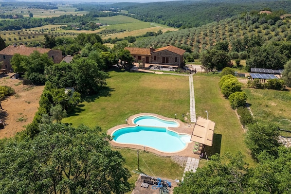 A house with a swimming pool, surrounded by a large grassy area and trees. - Apartment '2' with Shared Pool and Garden, Wi-Fi, and Air Conditioning (Massa Marittima)