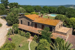 A stone building with a tiled roof, surrounded by greenery and a swimming pool. - Apartment '2' with Shared Pool and Garden, Wi-Fi, and Air Conditioning (Massa Marittima)