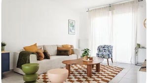 Sala de estar com sofá, mesa de centro e tapete estampado.