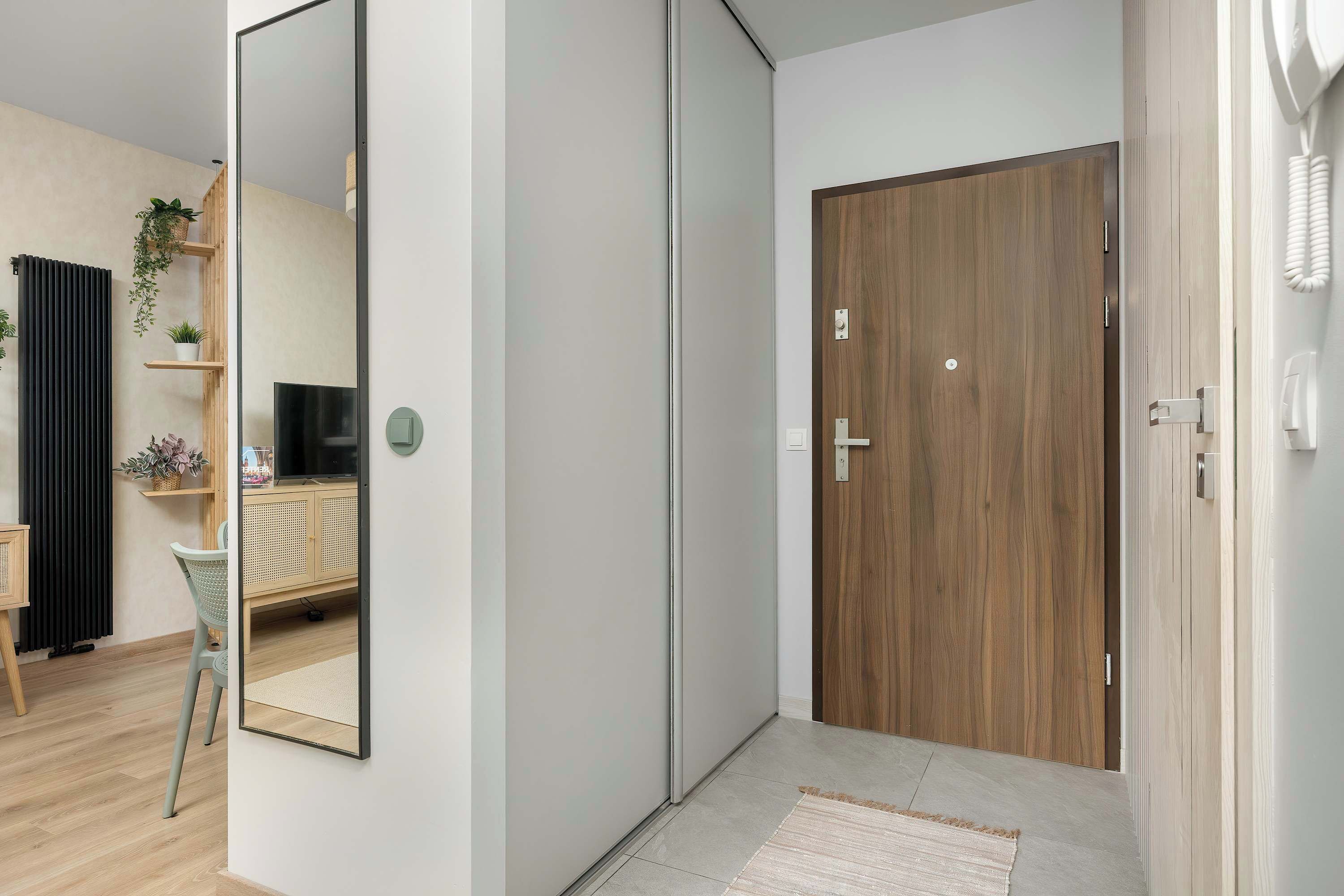 Une chambre moderne avec une porte en bois, un miroir, un petit bureau et une chaise.