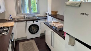 A compact kitchen with a washing machine, a sink, a window with a view, and a refrigerator. - APARTMENT 2 P ANTIBES - IDEAL VACATION FOR 2 (Antibes)