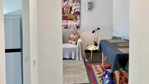 A modern room with a sofa, a small table, a patterned rug, and a tapestry on the wall. - APARTMENT 2 P ANTIBES - IDEAL VACATION FOR 2 (Antibes)