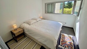 A bedroom with a bed, bedside lamps, a window, and a patterned rug. - APARTMENT 2 P ANTIBES - IDEAL VACATION FOR 2 (Antibes)