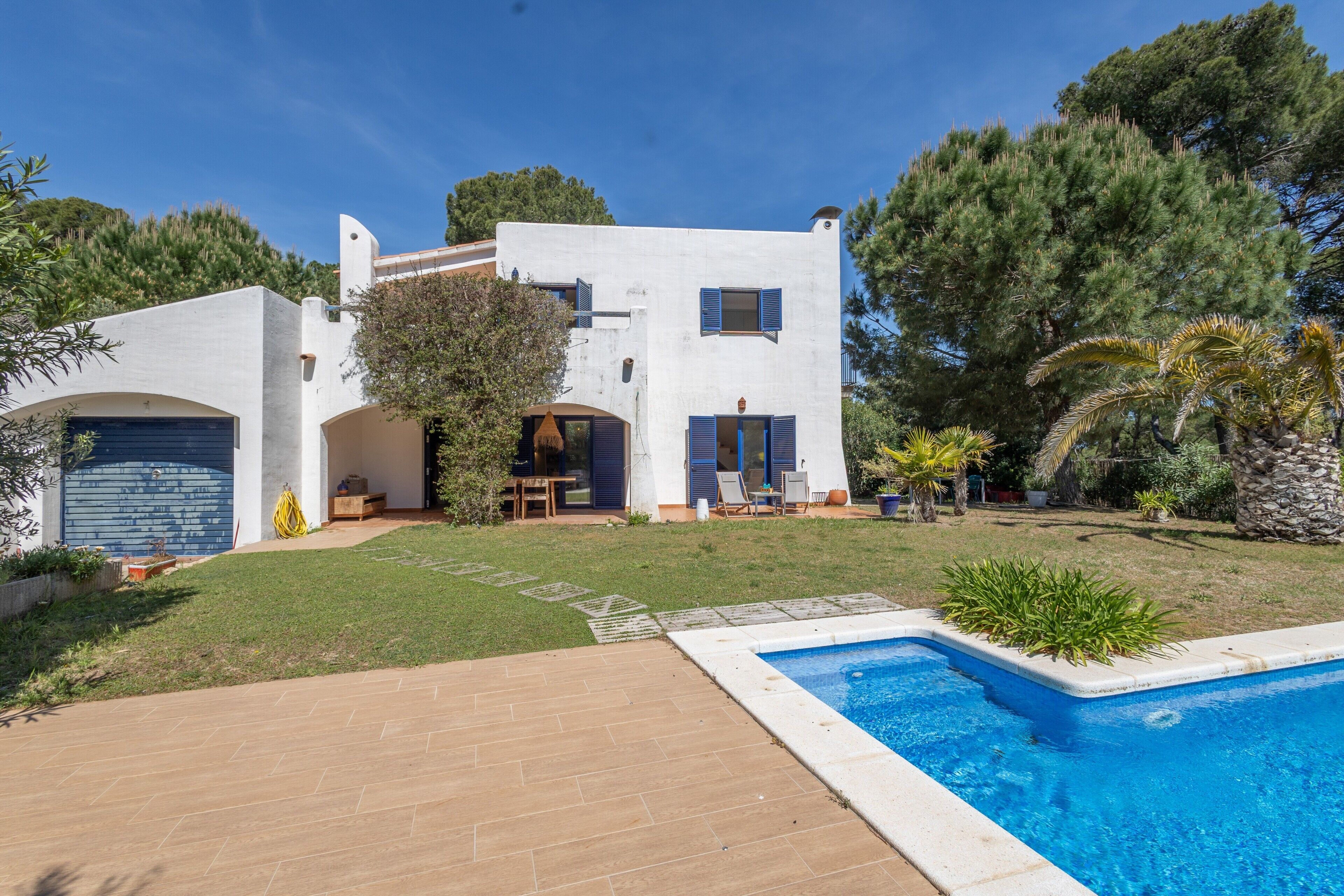 Une maison moderne dotée d’une piscine, d’un garage et d’une pelouse bien entretenue.