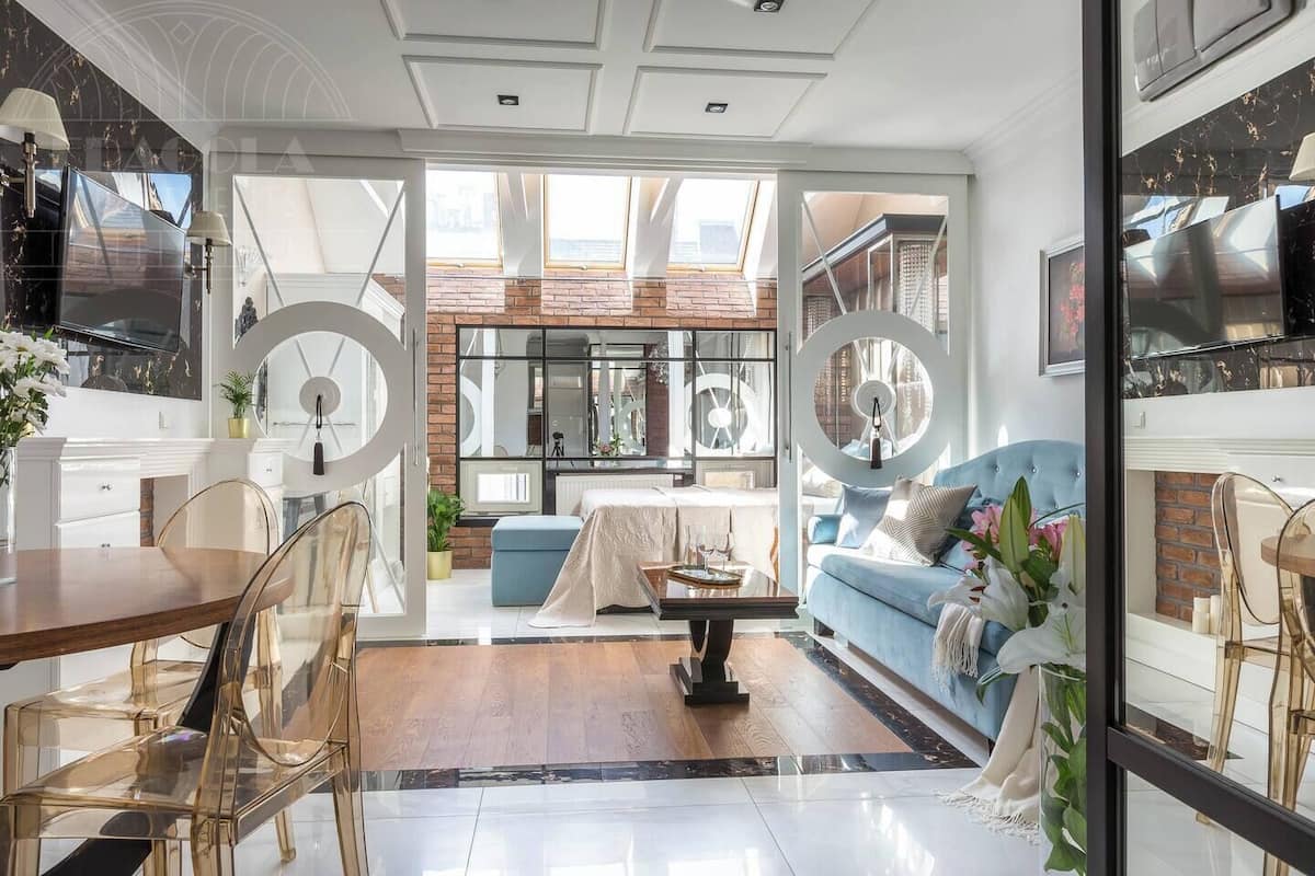 Ein modernes Wohnzimmer mit Essbereich, einem blauen Sofa und einem Kamin.