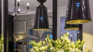 A bedroom with a bed, a mirror, a vase with flowers, and a chandelier. - The Eleven by Fragola Apartments (Kraków)