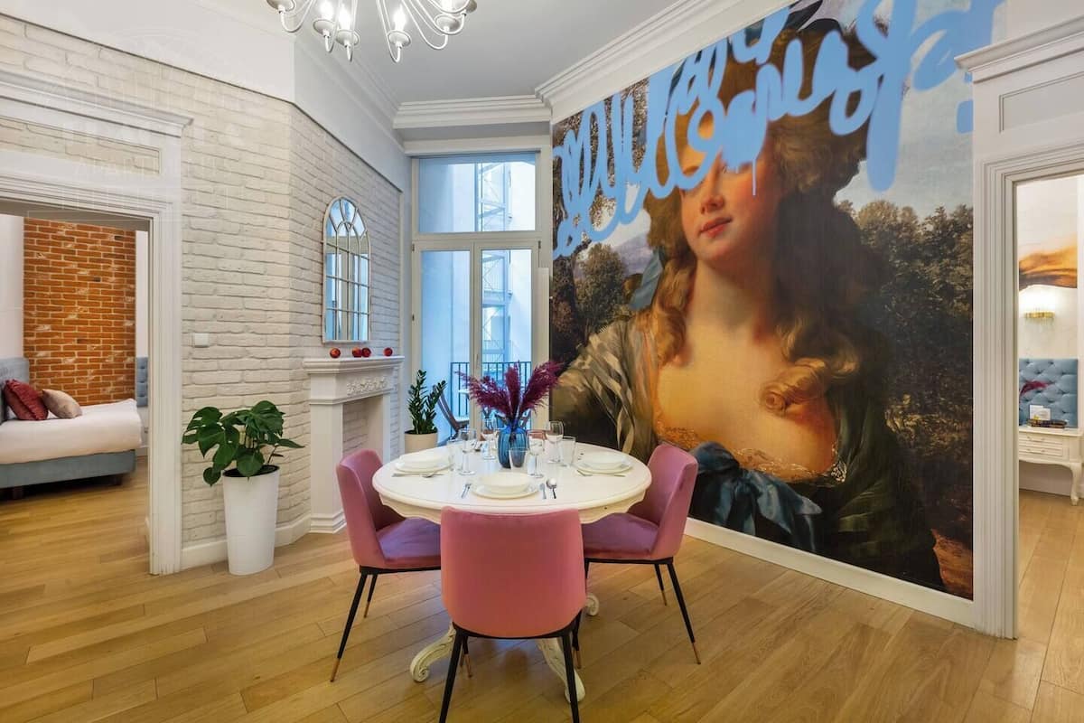Ein Essbereich mit einem runden Tisch, Stühlen und einem großen Gemälde an der Wand.