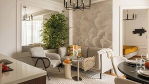 A modern living room with a sofa, armchairs, a coffee table, and a dining area with a table and chairs. - The Eleven by Fragola Apartments (Kraków)