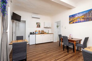 A modern kitchen with white cabinets, a wooden countertop, and a dining area with grey chairs.