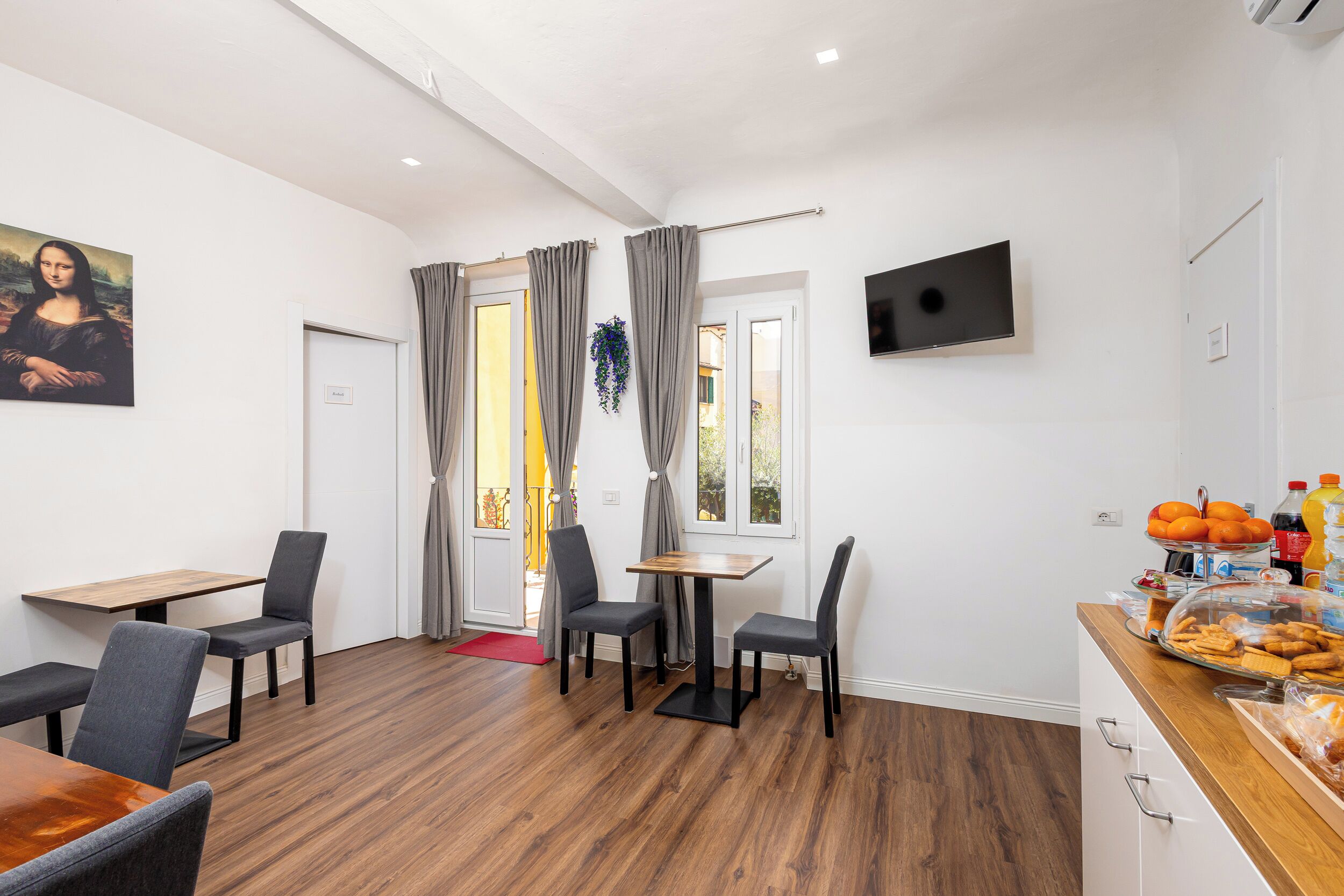 Un área de comedor con una mesa y sillas de madera, un cuadro en la pared y un mostrador de buffet con alimentos.