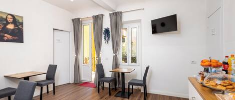Un área de comedor con una mesa y sillas de madera, un cuadro en la pared y un mostrador de buffet con alimentos.