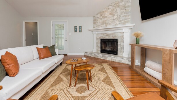A living room with a white sofa, a fireplace, a television, and a ceiling fan. - Pool + Fenced Yard | 4BR Family Home | Close to 96 (Warner Robins)