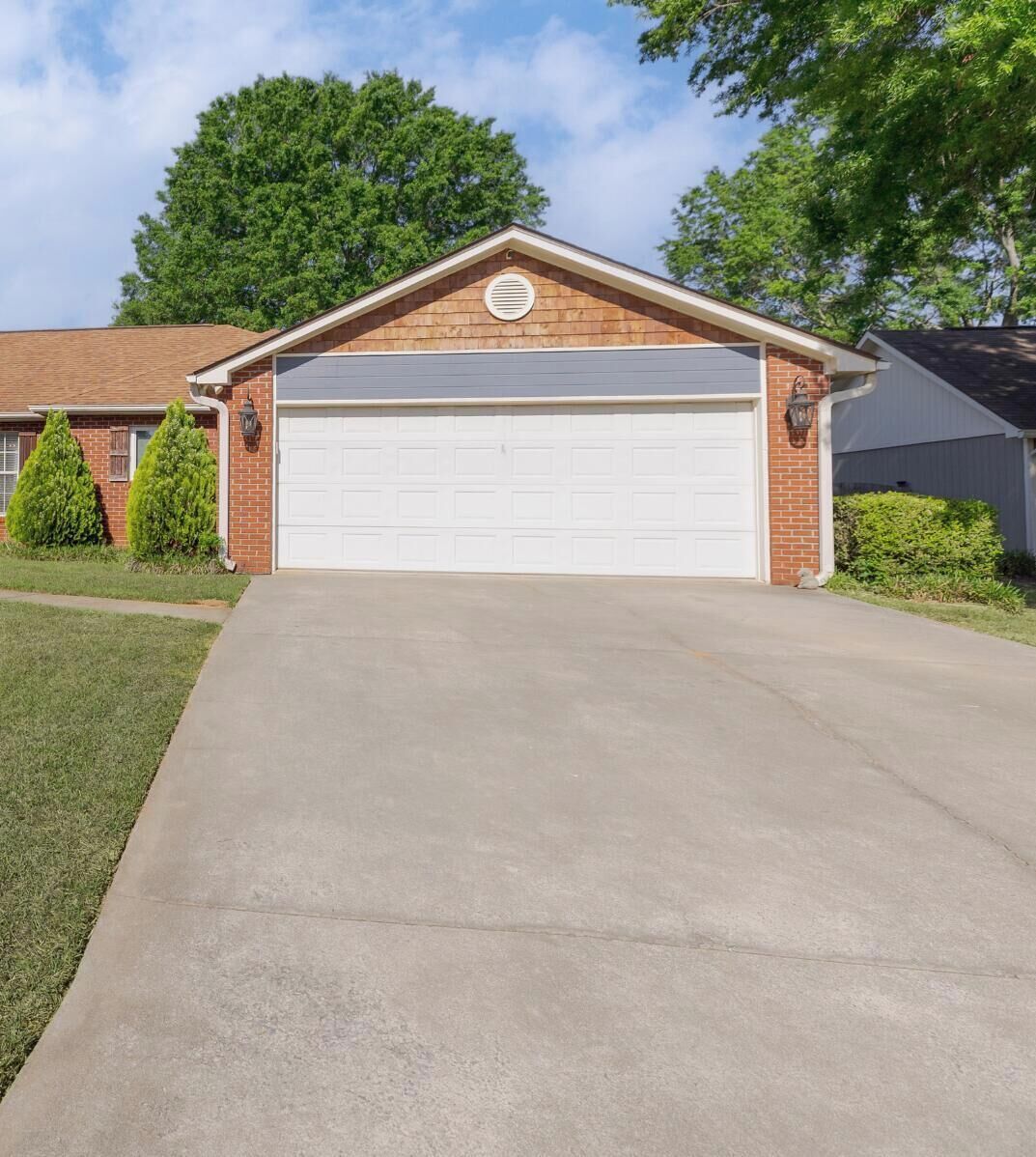 Ein bungalow mit Garage, einem Vorgarten und einem Baum im Hintergrund.