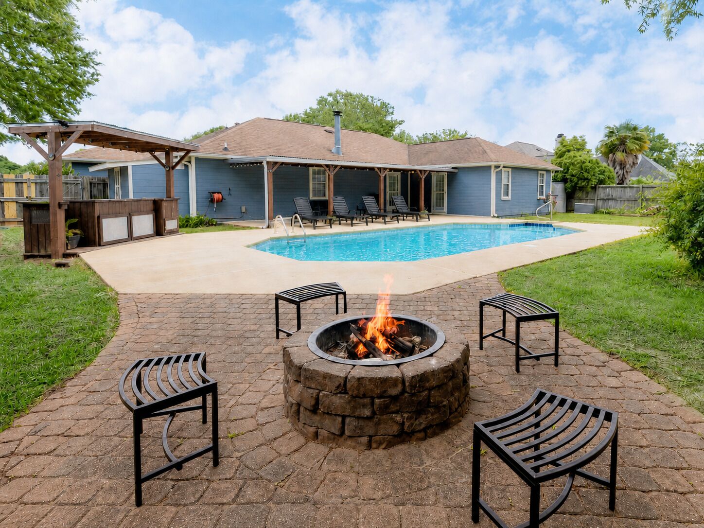 Ein Garten mit Pool, Feuerstelle und Gartenmöbeln.