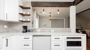 A modern kitchen with white cabinetry, a dishwasher, an oven, and a brick backsplash. - Pool + Fenced Yard | 4BR Family Home | Close to 96 (Warner Robins)