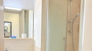 A bathroom with a glass-enclosed shower, a white sink, and a wooden vanity. - St Cyprien, right on the water, beach or swimming pool (Saint-Cyprien)