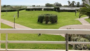 A balcony with a view of a well-maintained lawn, a white fence, and a clear sky. - St Cyprien, right on the water, beach or swimming pool (Saint-Cyprien)