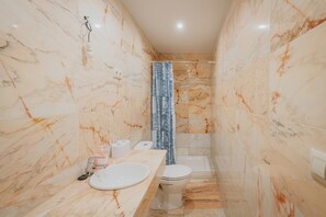 A bathroom with marble walls, a sink, toilet, and a shower curtain. - Los Mirlos Country House – Nature Retreat with Garden and Social Lounge (Navaluenga)