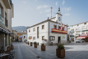 A plaza with a clock tower, outdoor seating, and potted plants. - Los Mirlos Country House – Nature Retreat with Garden and Social Lounge (Navaluenga)