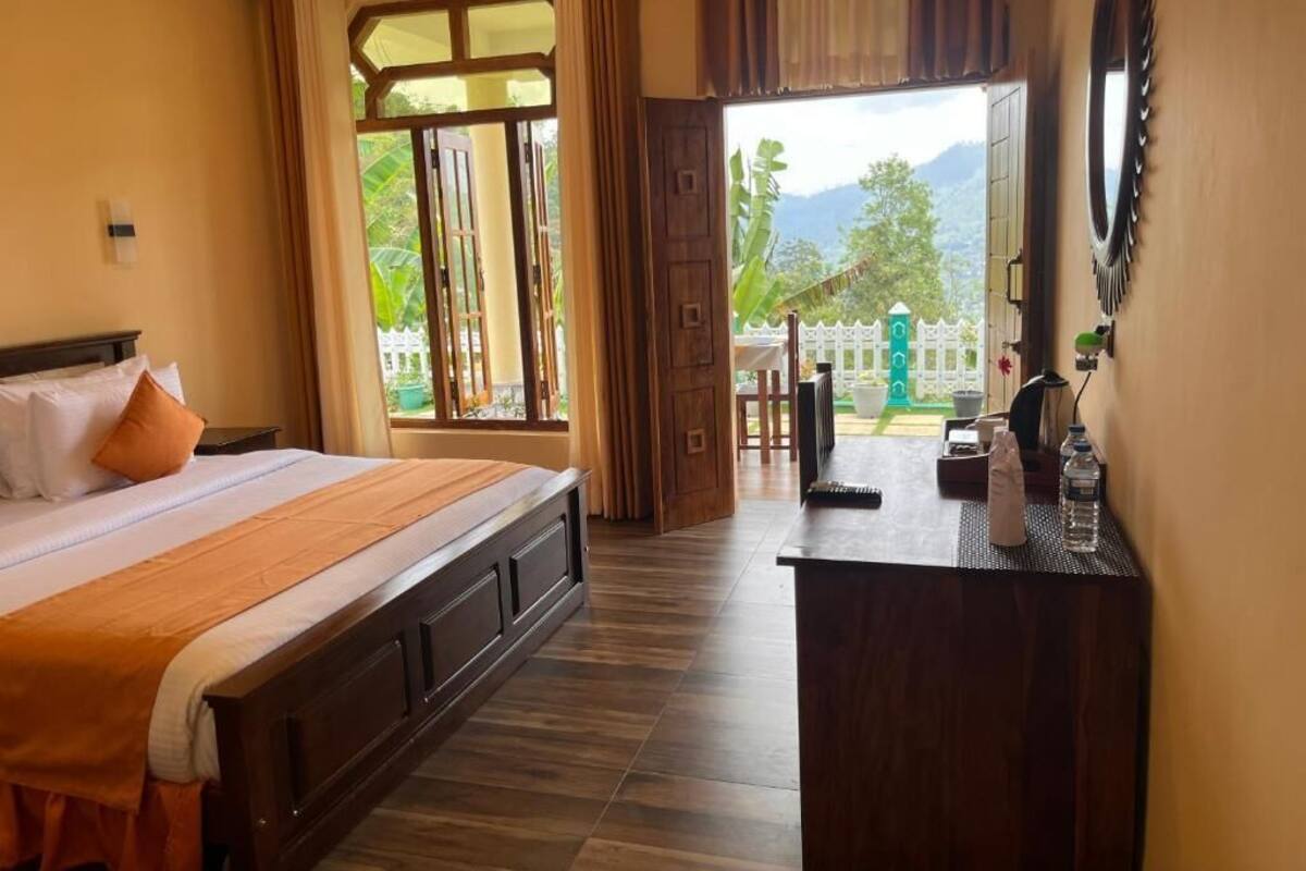 A hotel room with a bed, a desk, a mirror, and a view of the outdoors.
