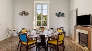 Une salle à manger dotée d’une grande fenêtre, d’une cheminée et d’un téléviseur.