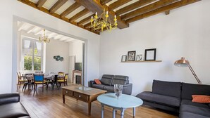 Un vaste salon doté d’un plafond en bois, d’un lustre, d’un canapé, d’une table basse et d’un coin repas avec une table et des chaises.