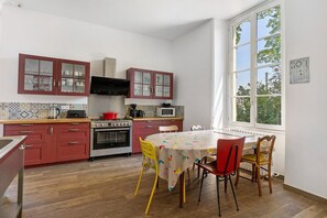 Une cuisine avec des meubles en bois, une table à manger avec des chaises et une fenêtre donnant sur les arbres.
