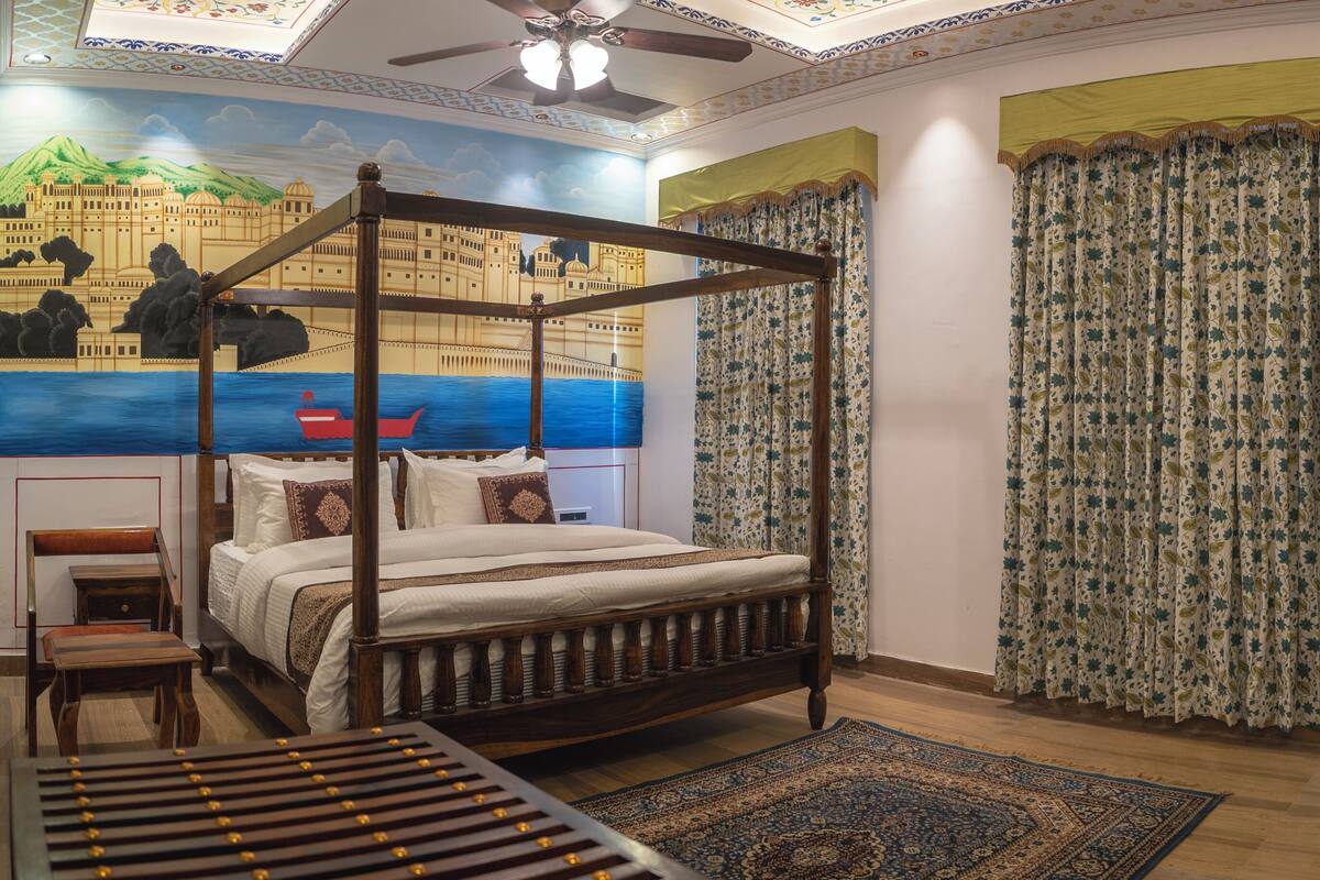 Una cama con dosel, una mesita de noche de madera, una pequeña mesa, un televisor y un mural en la pared.