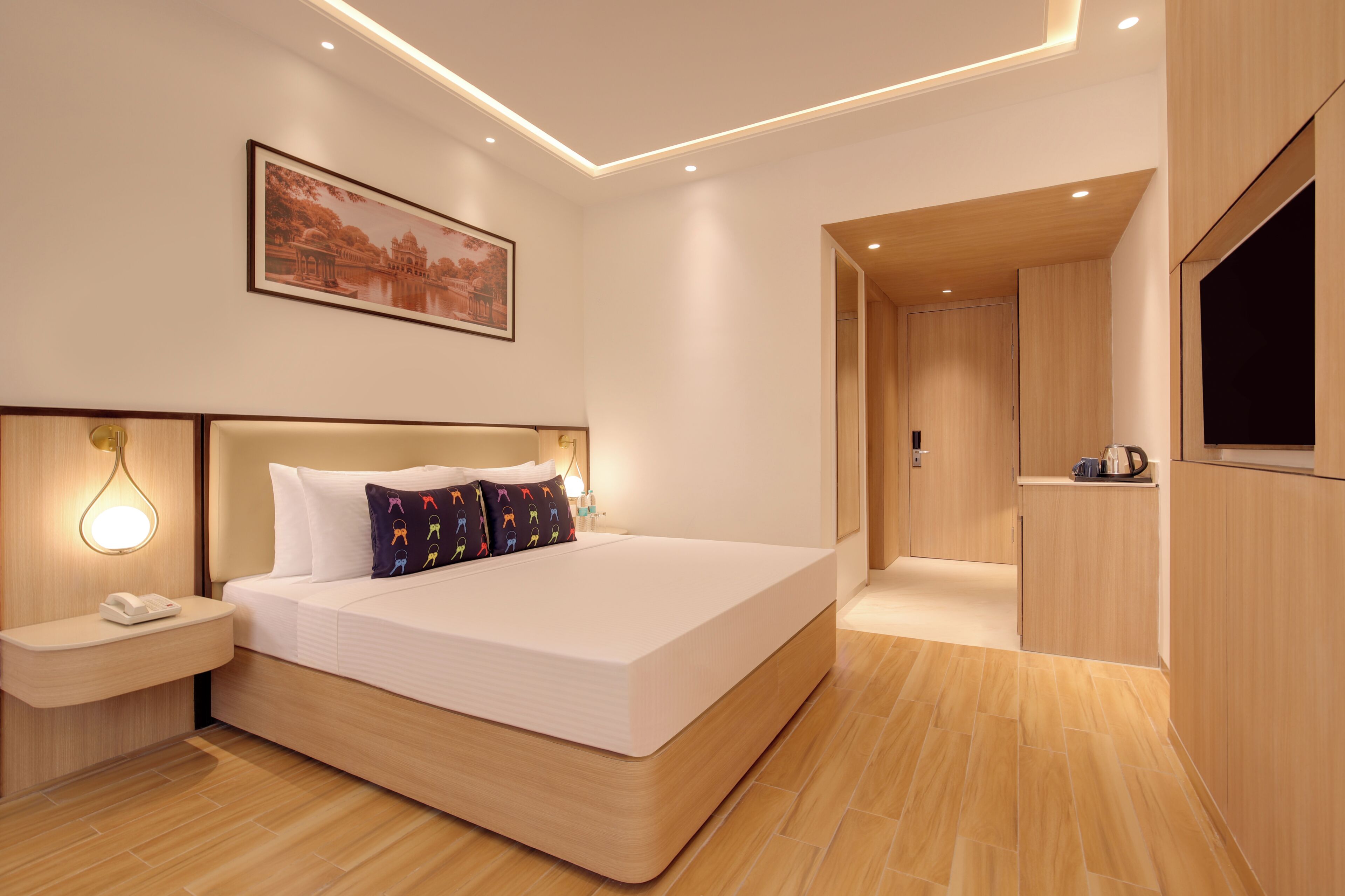 Una habitación de hotel moderna con una cama grande, una mesita de noche y un cuadro en la pared.