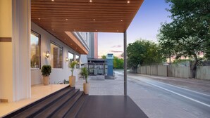 A modern hotel entrance with a covered walkway, steps, potted plants, and a view of the street. - Keys Select by Lemon Tree Hotel Amritsar (Amritsar)