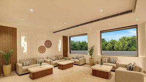 A modern living room with multiple sofas, a coffee table, and a large window with a view of greenery. - Keys Select by Lemon Tree Hotel Amritsar (Amritsar)