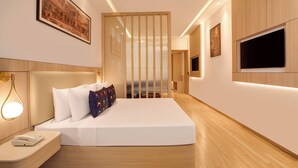 A modern hotel room with a large bed, bedside table, wall-mounted TV, and a decorative partition. - Keys Select by Lemon Tree Hotel Amritsar (Amritsar)