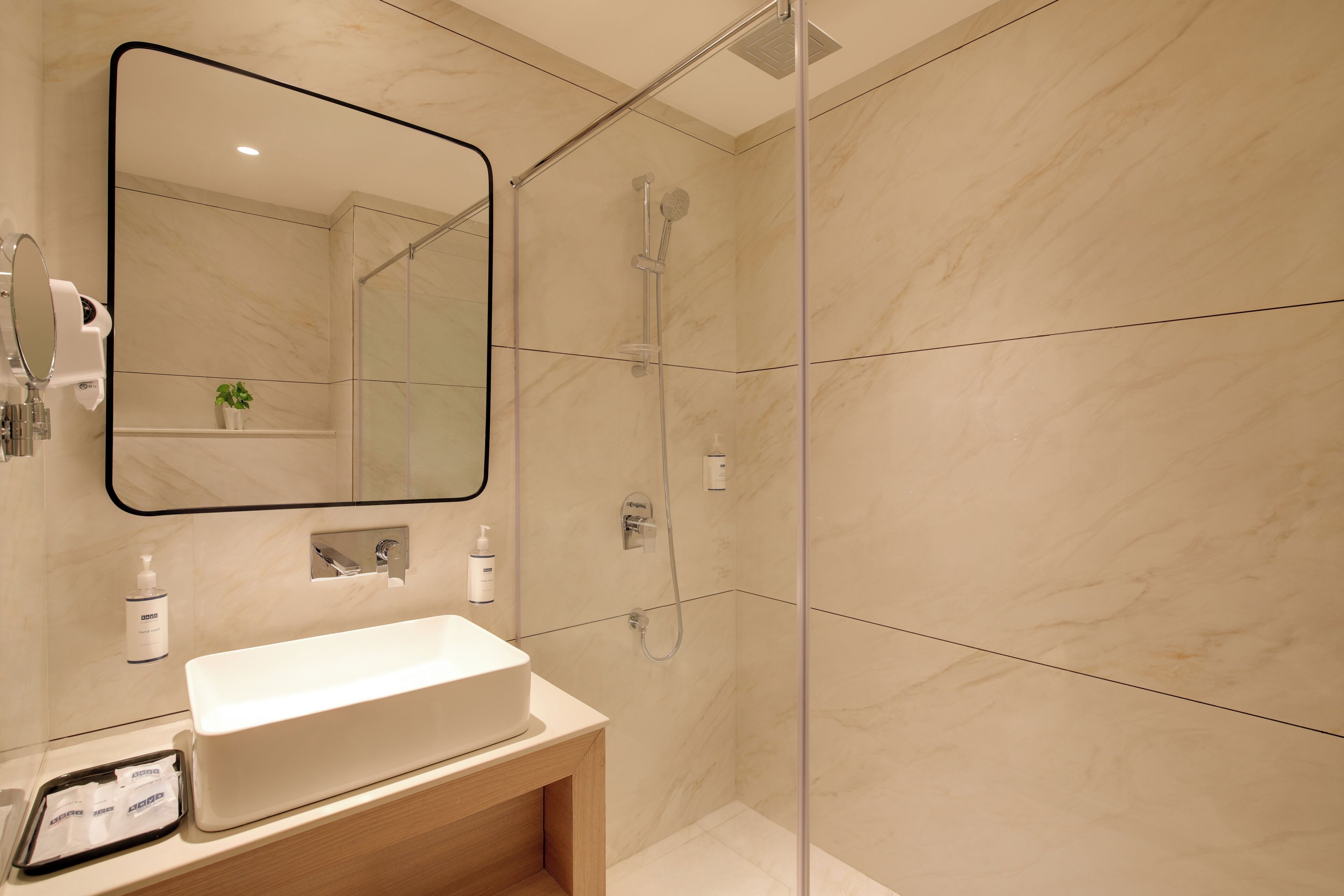 A modern bathroom with a large mirror, a sink, and a shower.